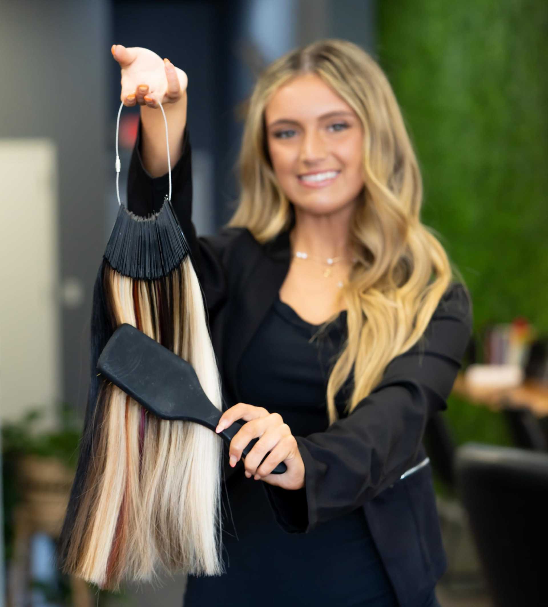 Young woman displaying a hair color palette in a salon setting.