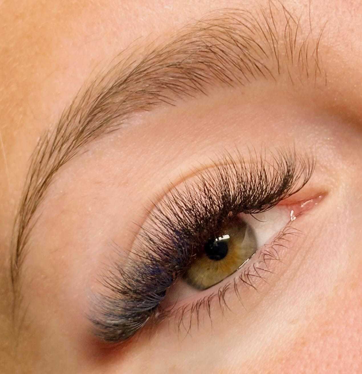 Close-up of an eye with long, curled eyelashes and natural makeup.